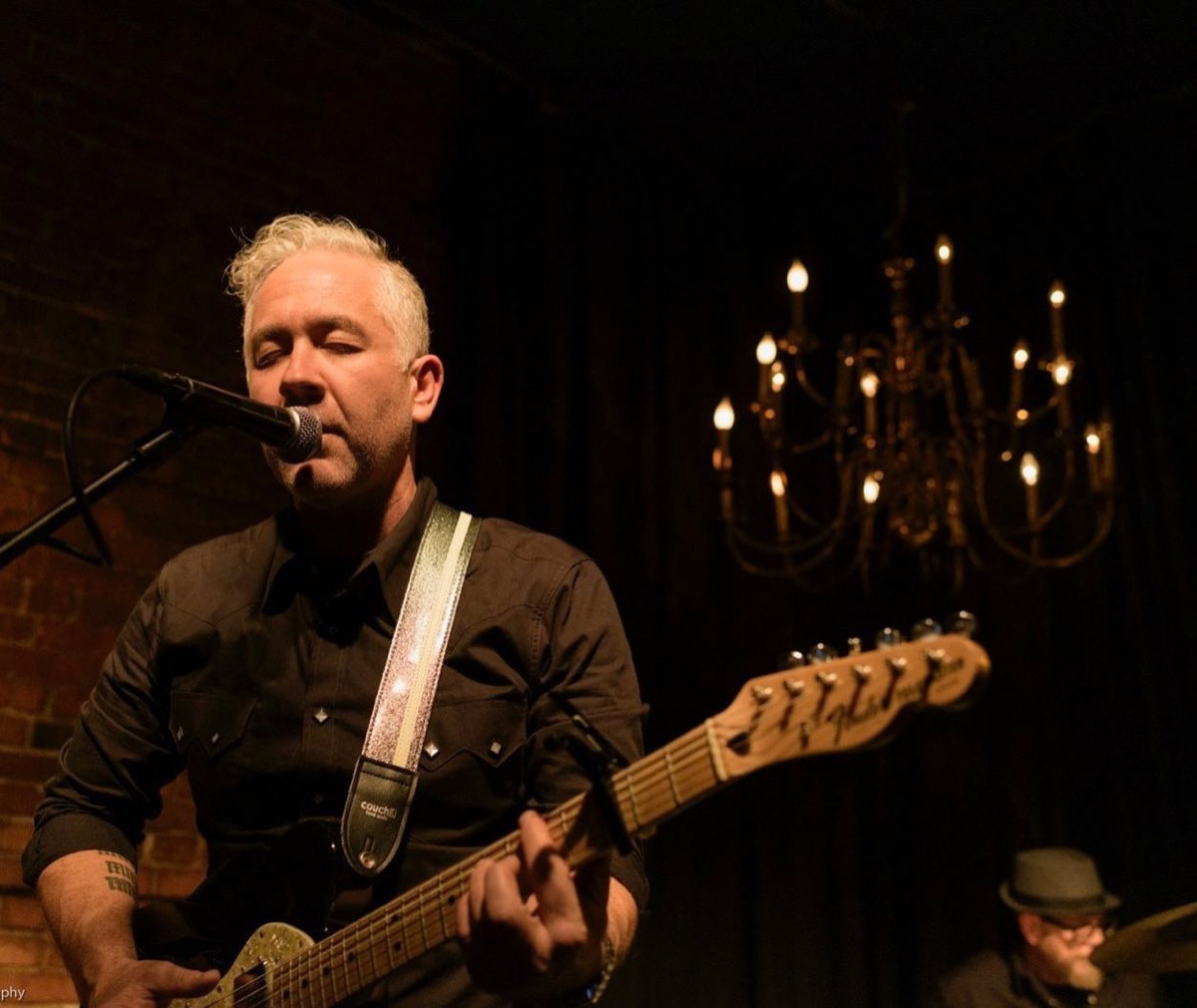 Knathan Ryan performing at a venue with chandelier